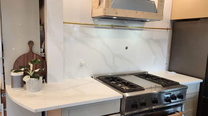 Curved white quartz counter beside a stainless steel gas range