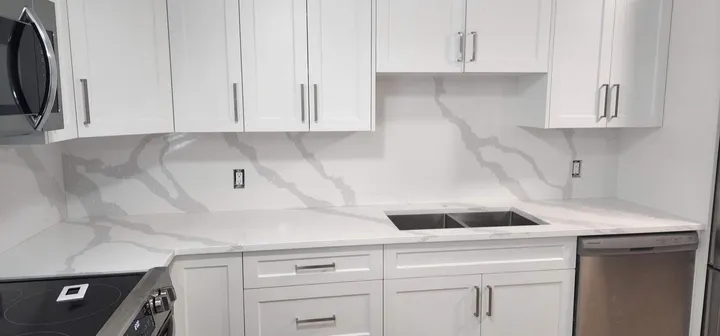 White kitchen with bold grey veined quartz counters, backsplash and double sink