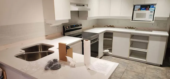 Pale quartz counters and double sink in a kitchen during installation