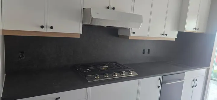 Charcoal quartz counters and backsplash surrounding a gas cooktop