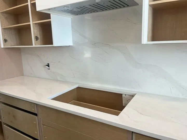 Softly veined white quartz counter and backsplash during kitchen installation