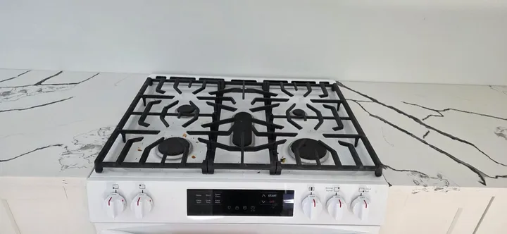 White gas range framed by black-veined white quartz counters