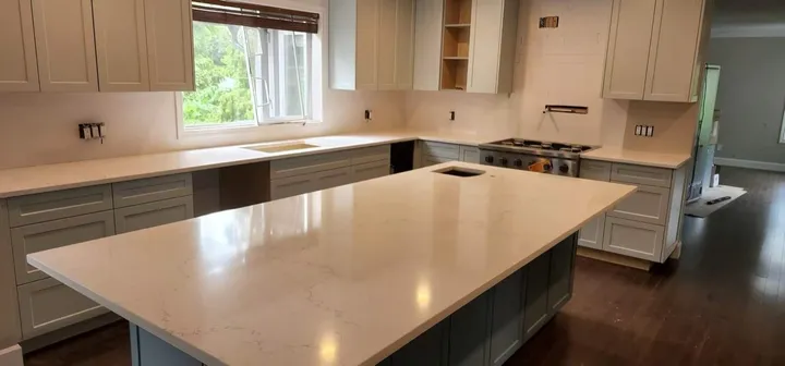 Large pale quartz island in a kitchen with grey cabinets