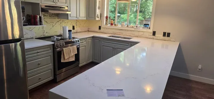 Wide view of a white quartz peninsula and matching kitchen counters